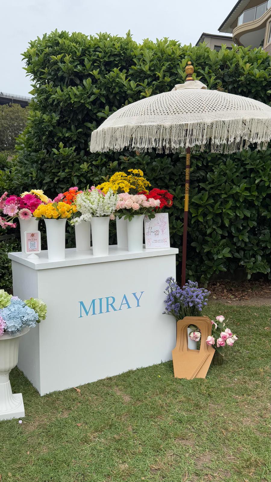 MIRAY flower bar with colourful fresh flowers beneath a white fringed umbrella